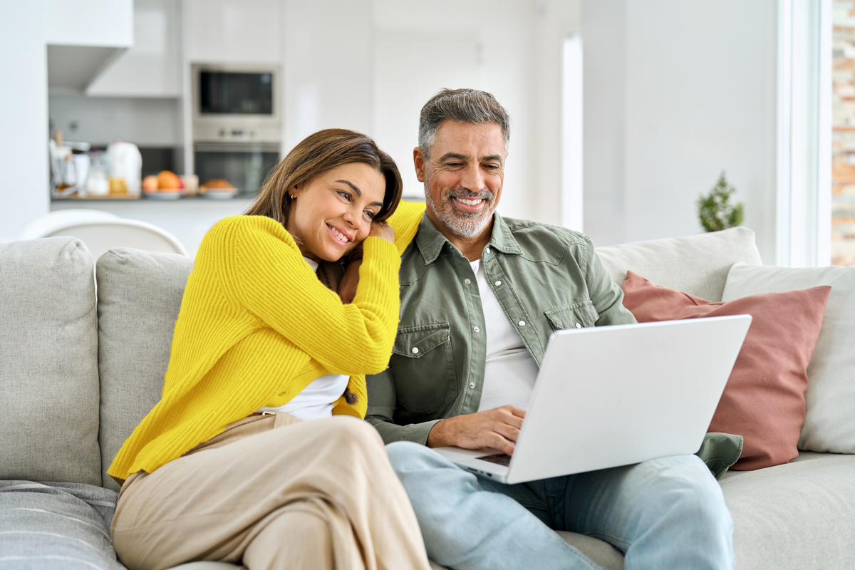 Happy couple looking at their phone and electricity bill