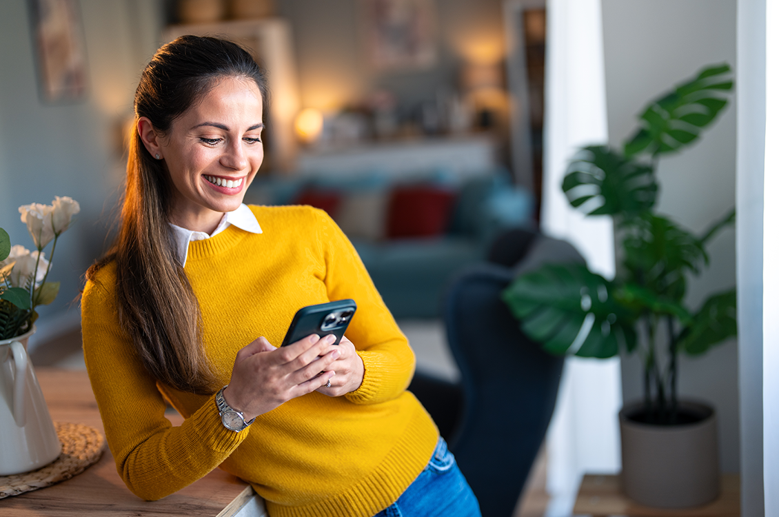 Young woman smiling while looking at the Discount Power app on her phone. 