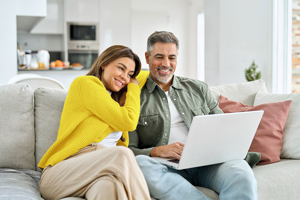 Happy couple looking at their phone and electricity bill